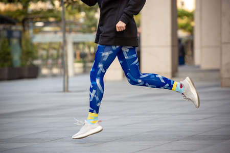Crop portrait of young female in bright sportswear doing running outdoors.