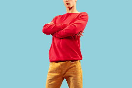 Young man in bright colored clothes posing on blue studio background.の写真素材
