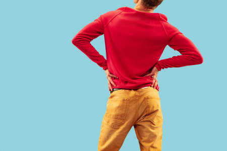 Young man in trendy colored clothes posing on blue studio background. Back viewの写真素材