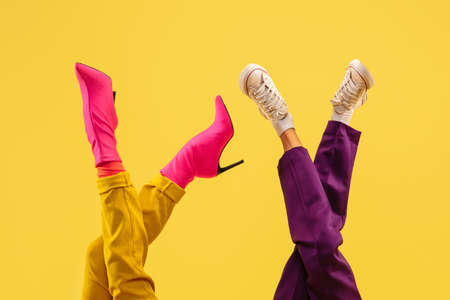 Fashion models feet in bright stylish footwear isolated on yellow background.の写真素材