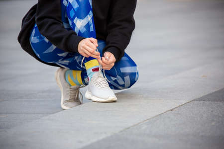 Female fitness runner tying sportshoe laces. Close-up hands and legs.の写真素材