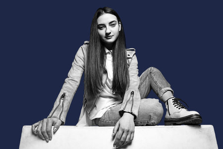 Young beautiful girl posing isolated over dark blue background. White and black.の写真素材