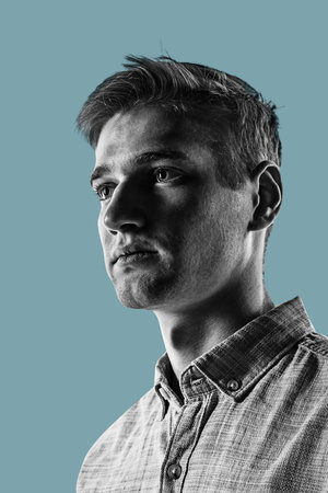 Close-up portrait of handsome young man isolated over blue background.の写真素材