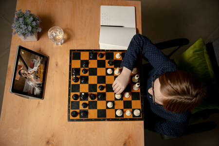 Little Caucasian boy chess player playing chess online using laptop.