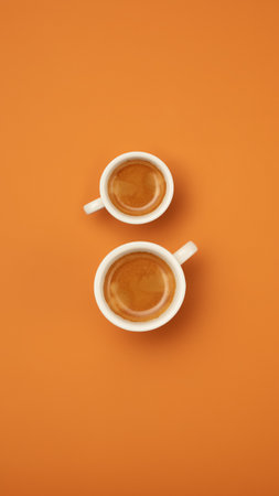 Two cups of coffee in shape of number 8 isolated over orange background.の写真素材