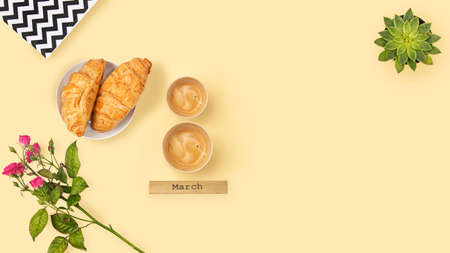 Two cups of coffee in shape of number 8 and croissants over light background.
