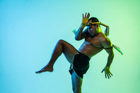 Young man thai boxer training over blue background in neon light.の写真素材
