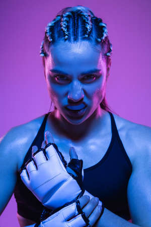 Close-up portrait of athletic girl MMA fighter isolated on blue backgroundの写真素材