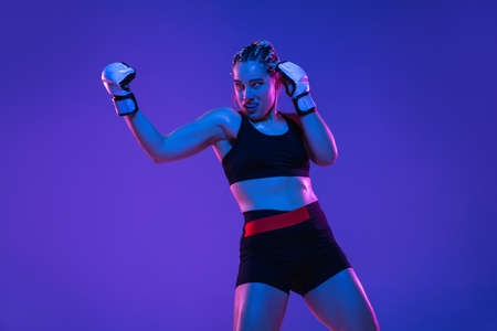Athletic female MMA fighter training over blue-pink background in neon lightの写真素材