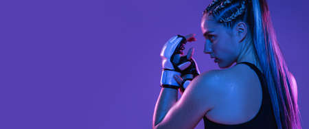 Close-up portrait of athletic girl MMA fighter isolated on blue backgroundの写真素材
