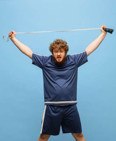 Funny red-headed man in blue sports uniform isolated on blue background