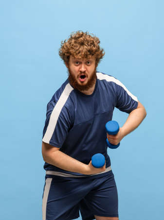 Funny red-headed man in blue sports uniform isolated on blue backgroundの写真素材