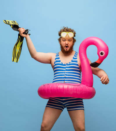 Funny red-headed man in swimming suit isolated on blue background.の写真素材