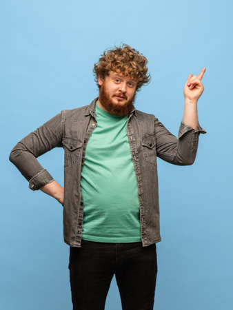Happy young red-headed man in casual clothes isolated on blue background.の写真素材