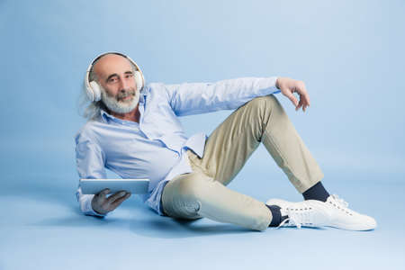 Senior grey-haired man with tablet, device isolated over light background.