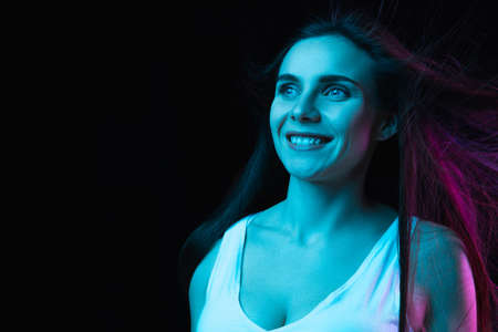 Portrait of young beautiful girl isolated on dark background in neon lightの写真素材