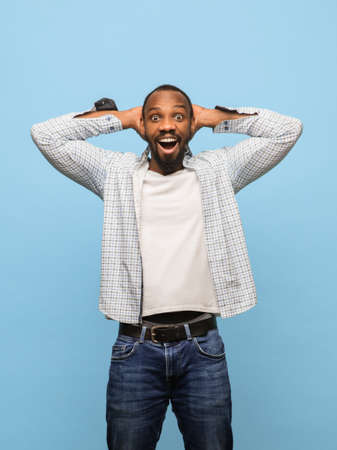 Happy African-American man in casual clothes isolated over blue background.の写真素材