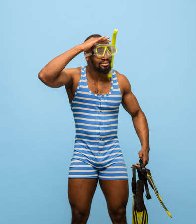 Funny Africam-American man in swimming suit, goggles isolated on blue backgroundの写真素材