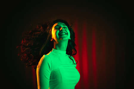 Portrait of smiling girl isolated on multicolored background in neon light.