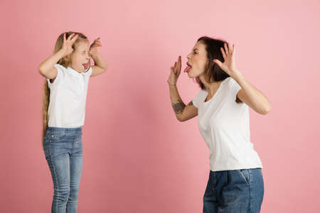 Happy woman and little girl, mother and daughter isolated over pink background.