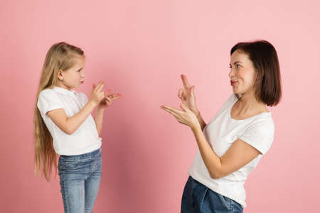 Portrait of woman and girl, mother and daughter isolated over pink background.の写真素材