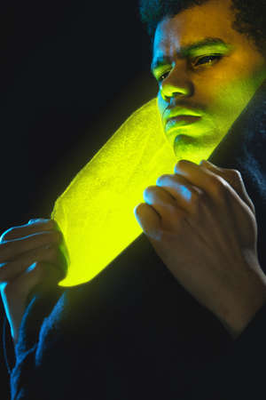 Portrait of African-American young man isolated on dark background in neon lightの写真素材