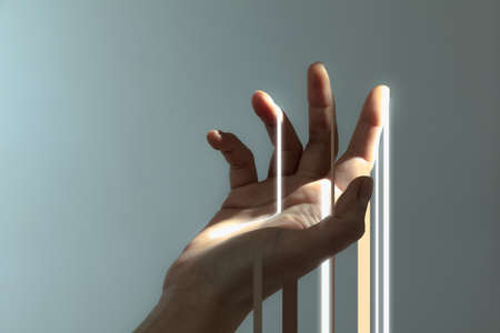 Beautiful female hand catching streaks of light isolated on grey background.