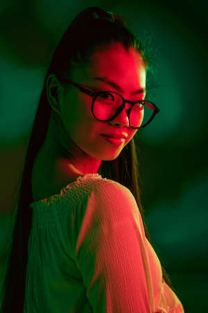 Young pretty Asian girl isolated over red green neon light background.