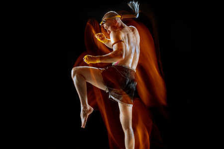 Young man thai boxer training over dark background in neon mixed light.の写真素材