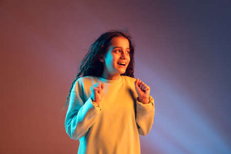 Portrait of young beautiful girl isolated on gradient background in neon light