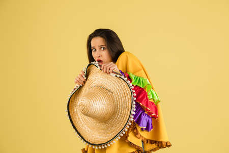Young beautiful girl with sombrero isolated over yellow background.の写真素材