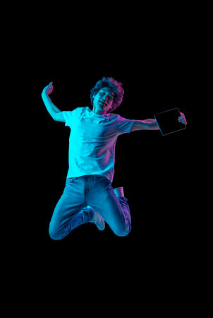 Portrait of young man with tablet isolated over dark background in neon light
