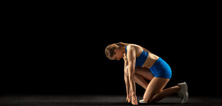 Young woman, track athlete training isolated over black studio background.の写真素材