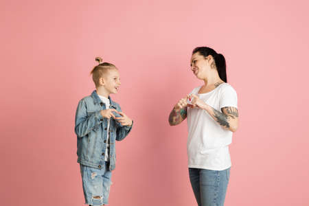 Young woman and little boy, mother and son isolated over pink background.