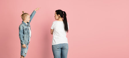 Young woman and little boy, mother and son isolated over pink background.