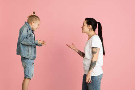 Young woman and little boy, mother and son isolated over pink background.の写真素材