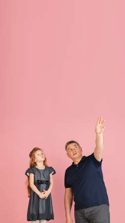 Two people, man and little girl, dad and daughter isolated over pink background.の写真素材