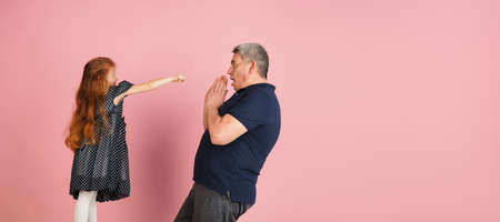 Two people, man and little girl, dad and daughter isolated over pink background.の写真素材