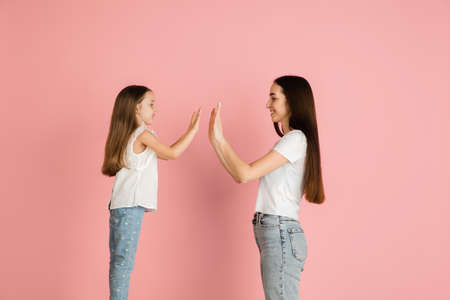 Two happy people, mother and daughter isolated over pink background.