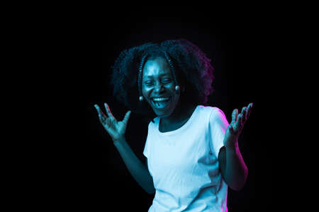 Young beautiful African-American girl isolated on dark background in neon light