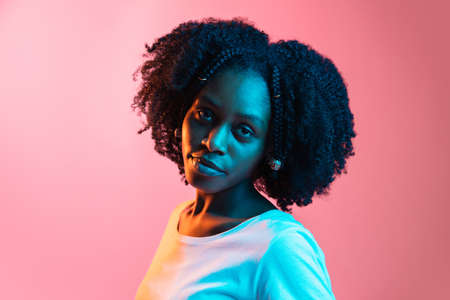 Young beautiful happy African-American girl isolated on pink background in neon.