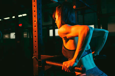 Young athletic woman, fitness instructor training in gym in mixed neon light.の写真素材