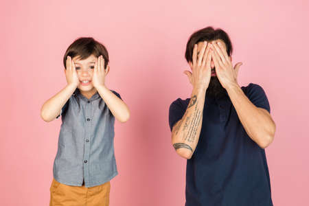Young man and little boy, father and son isolated over pink background.