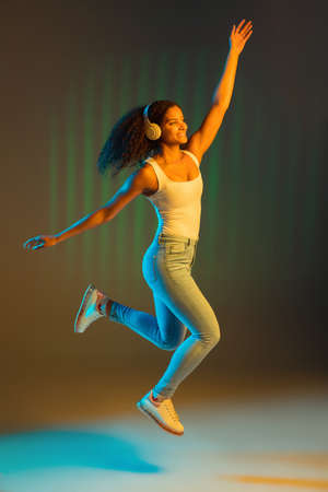 Young happy African-American girl isolated on colored background in neon.の写真素材