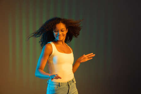 Young happy African-American girl isolated on colored background in neon.