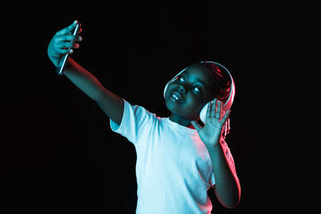 Portrait of little African-American girl isolated on dark background in neonの写真素材
