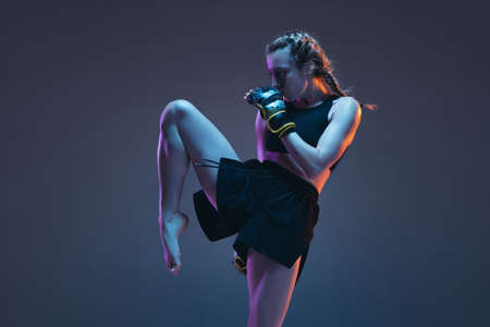 Caucasian female MMA fighter training isolated on blue background in neon lightの写真素材