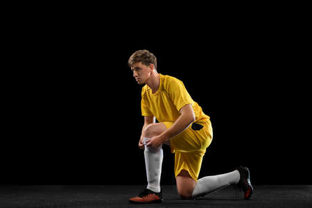 Portrait of male soccer football player posing isolated on black background.の写真素材