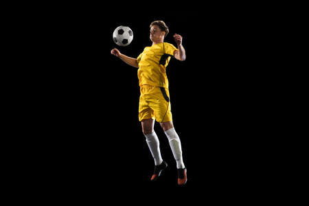 Young man, male soccer football player training isolated on black background.の写真素材