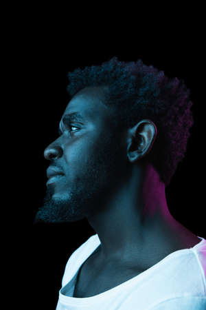 Young African-American man isolated on dark background in neon light